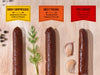 Three plant-based salami on a wood cutting board