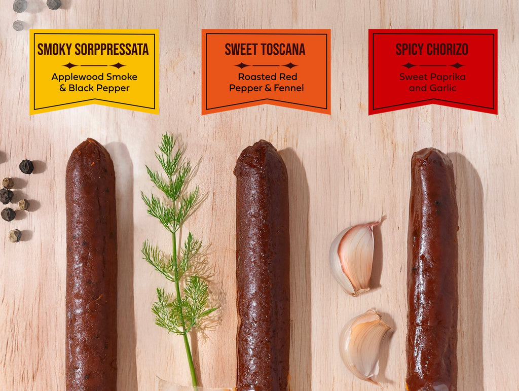 Three plant-based salami on a wood cutting board